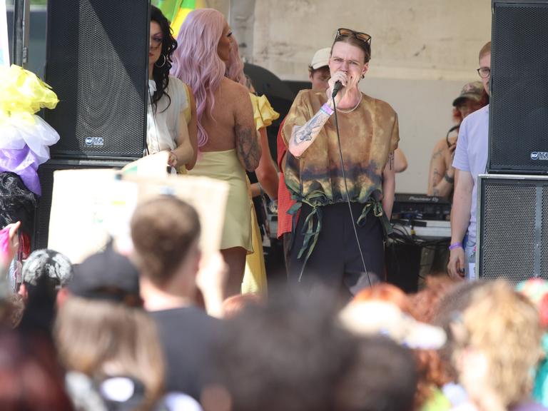 Luna Möbius steht auf der Bühne beim CSD in Leipzig und spricht am Mikrofon. Im Vordergrund steht das Publikum. Luna Möbius steht auf der Bühne beim CSD in Leipzig und spricht am Mikrofon. Im Vordergrund steht das Publikum.