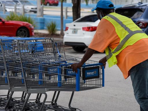 Ein Walmart-Mitarbeiter in Florida schiebt Einkaufswägen über einen Parkplatz.