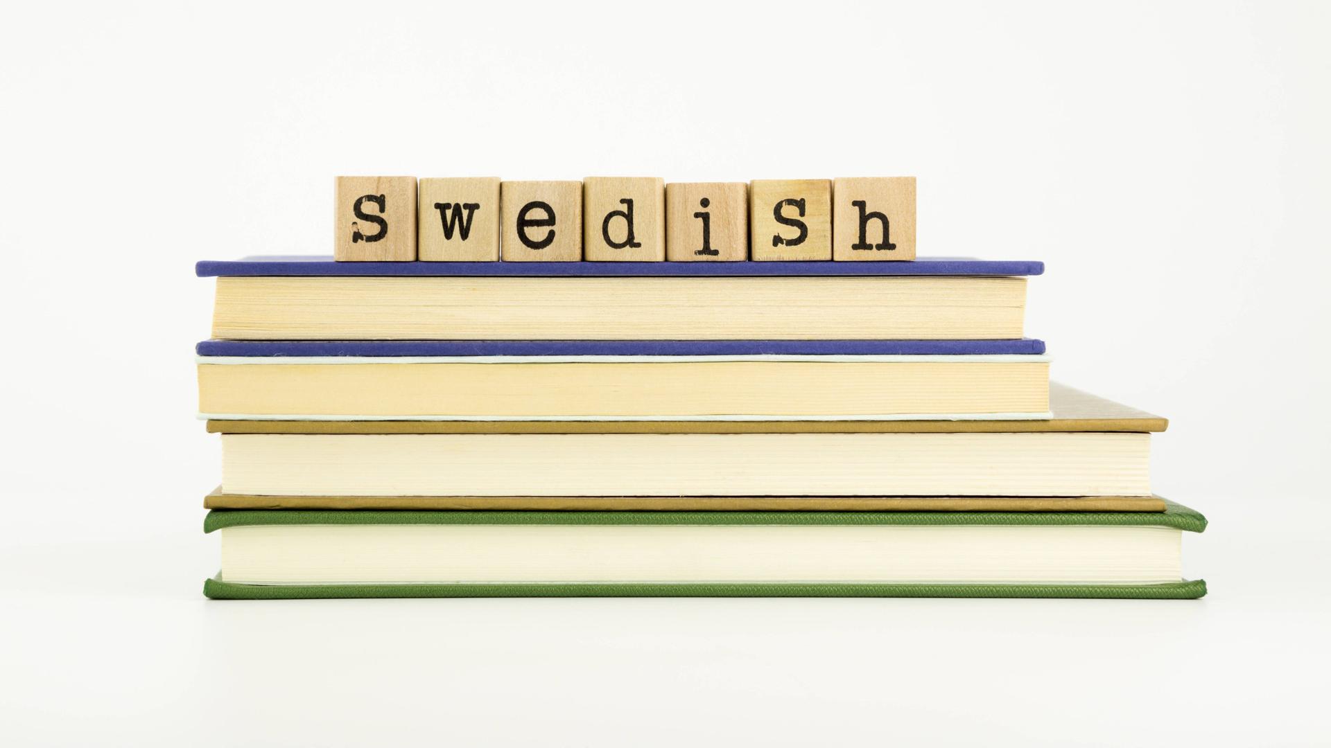 Vier Bücher liegen übereinander, darauf in Holzklötzen das Wort "swedish". Vier Bücher liegen übereinander, darauf in Holzklötzen das Wort "swedish".