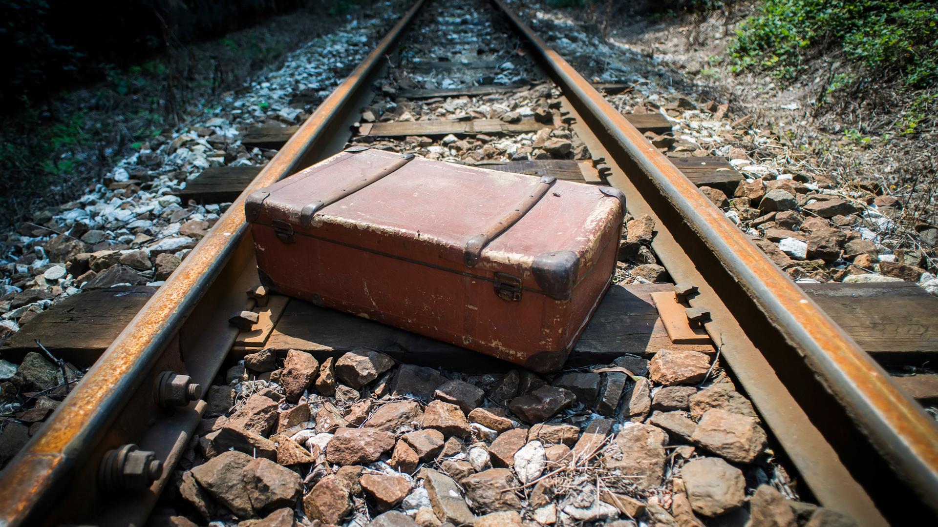 Gewaltsame Abschiebung durch die Nationalsozialisten: Blick auf Bahngleise und einen liegen gebliebenen Koffer