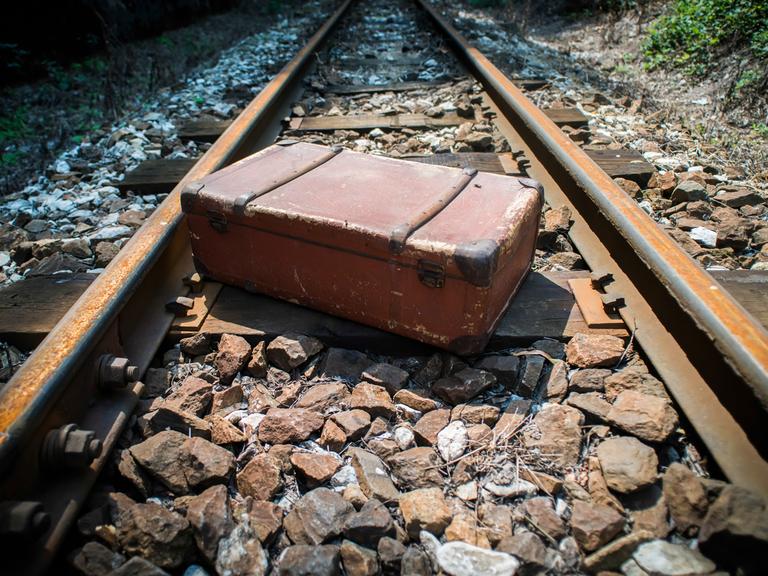 Gewaltsame Abschiebung durch die Nationalsozialisten: Blick auf Bahngleise und einen liegen gebliebenen Koffer