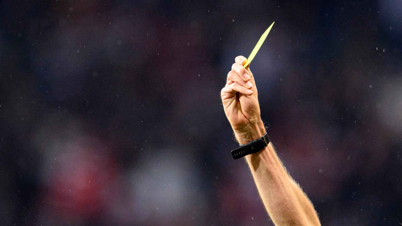 Die Hand eines Schiedsrichters zeigt die Gelbe Karte.