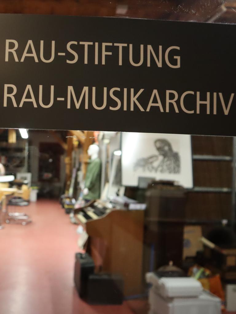 Blick in einen Raum, in dem im Vordergrund ein großes Schild prangt mit der Aufschrift "Lippmann und Rau-Stiftung" und "Lippmann und Rau-Musikarchiv". Im Hintergrund kann man schemenhaft eine Porträtradierung sehen und ein abgestelltes Grammophon.