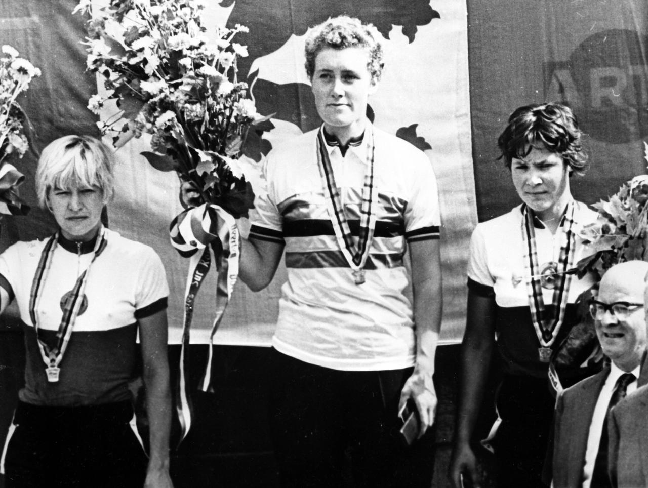 Drei Radrennfahrerinnen stehen auf einem Siegerpodest. 
