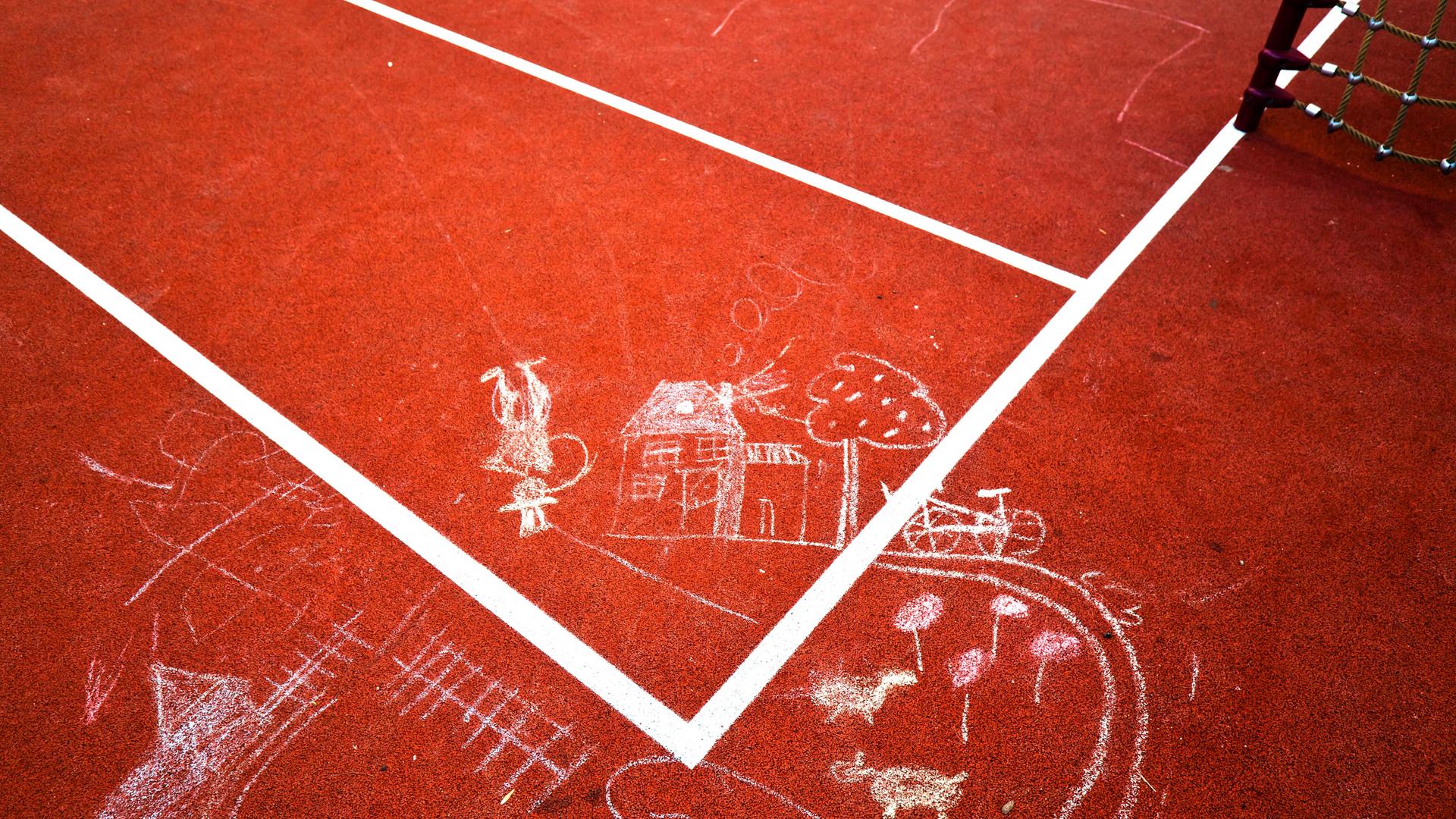 Kinderzeichnungen aus Kreide sind auf einen Tartanplatz gemalt.