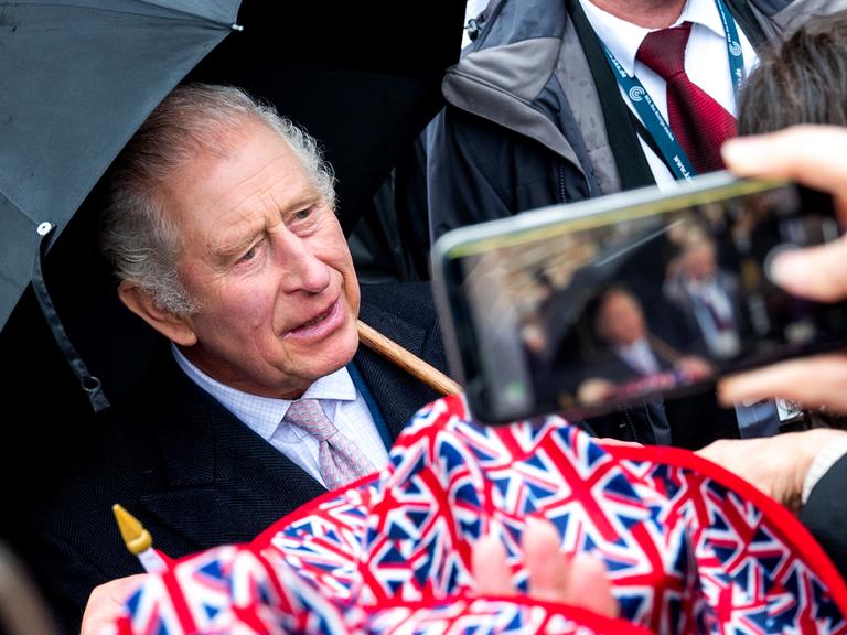 König Charles III. steht bei seinem Deutschlandbesuch in Hamburg vor Zuschauern mit Großbritannien-Flaggen 