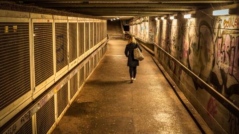 Eine Frau geht abends allein durch eine Unterführung.