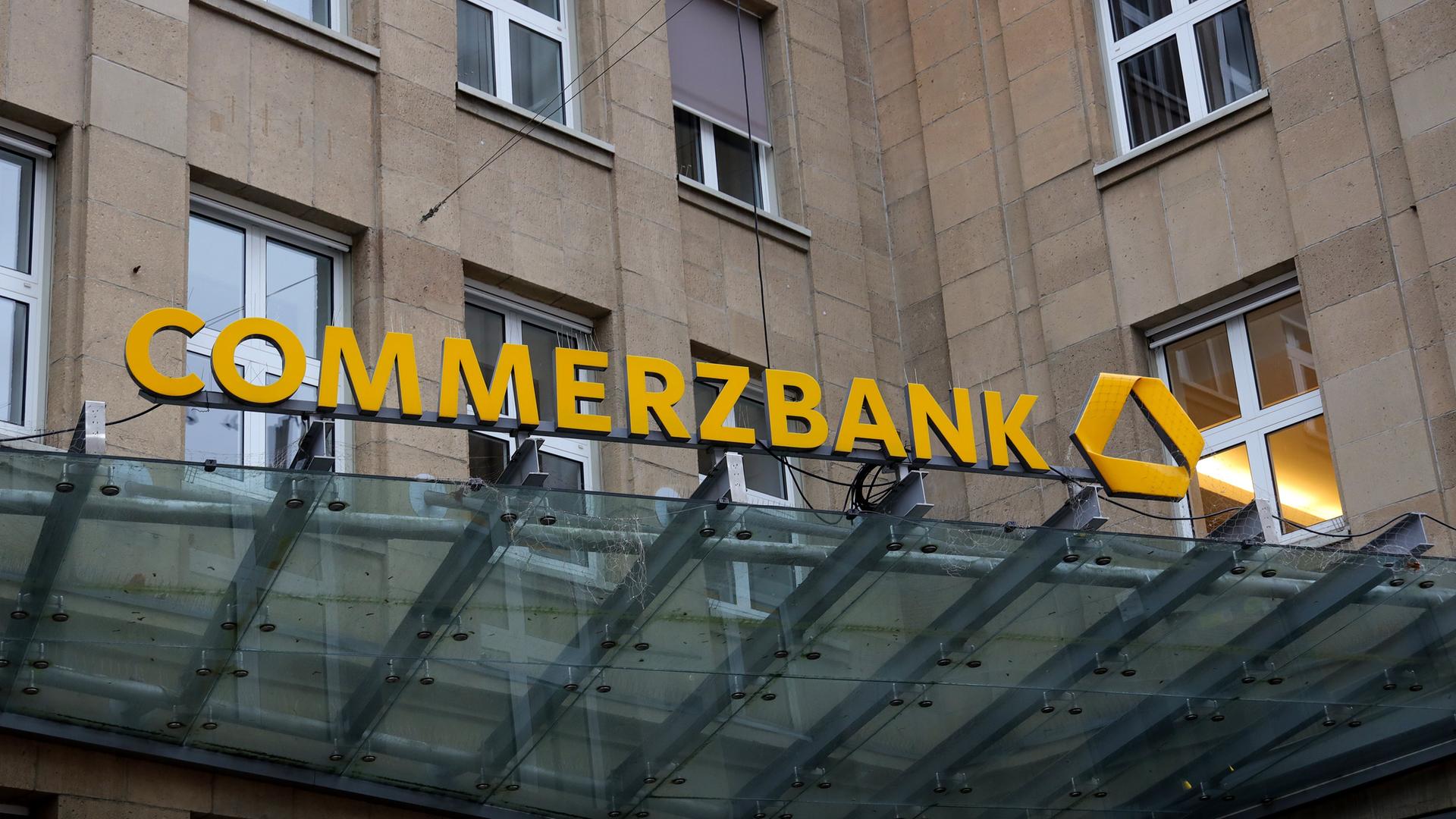 Das Eingangsportal einer Commerzbankfiliale mit dem Schriftzug "Commerzbank" in einem steinernen Gebäude.