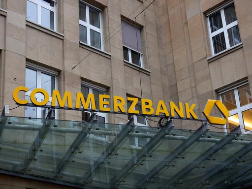Das Eingangsportal einer Commerzbankfiliale mit dem Schriftzug "Commerzbank" in einem steinernen Gebäude.