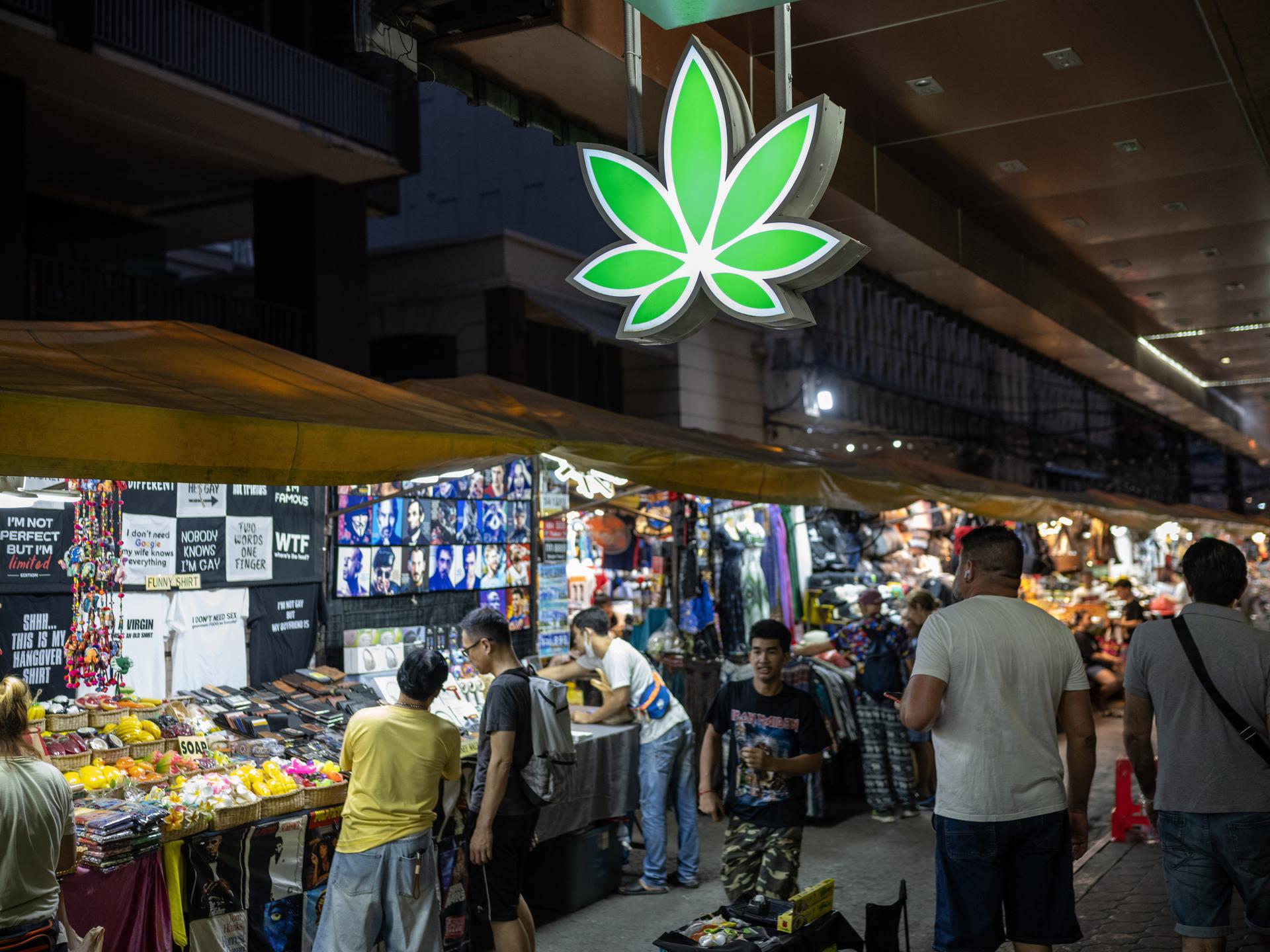 Ein leuchtendes, neongrünes Cannabisblatt-Schild auf dem Patpong-Nachtmarkt im Zentrum von Bangkok.