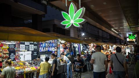 Ein leuchtendes, neongrünes Cannabisblatt-Schild auf dem Patpong-Nachtmarkt im Zentrum von Bangkok.
