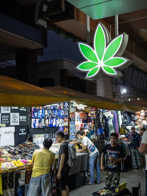 Ein leuchtendes, neongrünes Cannabisblatt-Schild auf dem Patpong-Nachtmarkt im Zentrum von Bangkok.