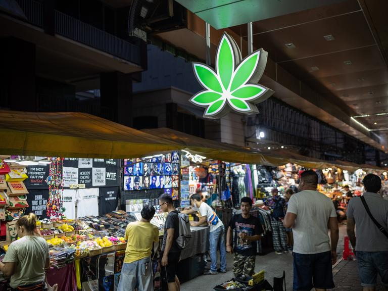 Ein leuchtendes, neongrünes Cannabisblatt-Schild auf dem Patpong-Nachtmarkt im Zentrum von Bangkok.