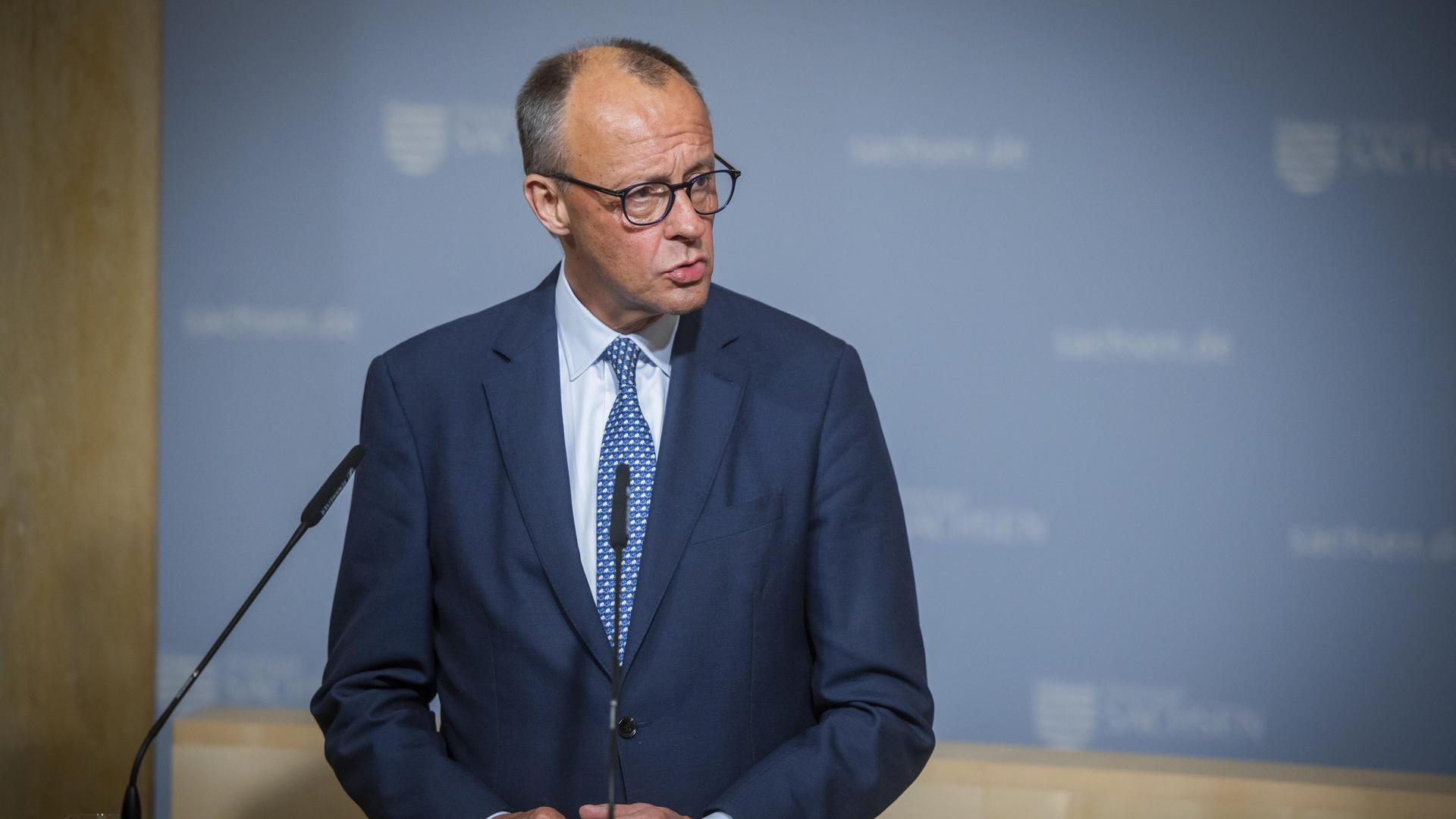 Bundeskanzler Friedrich Merz steht an einem Rednerpult und schaut zur Seite