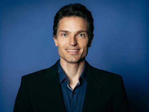 Enzo Weber posiert vor einem blauen Hintergrund für ein Pressefoto. Enzo Weber posiert vor einem blauen Hintergrund für ein Pressefoto.