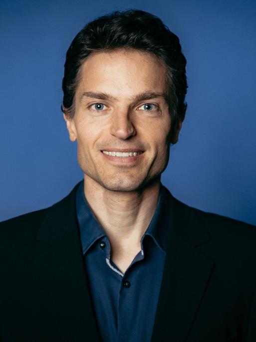 Enzo Weber posiert vor einem blauen Hintergrund für ein Pressefoto. Enzo Weber posiert vor einem blauen Hintergrund für ein Pressefoto.