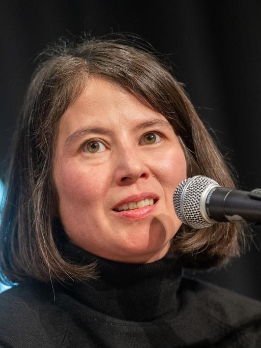 Die Autorin Milena Michiko Flasar spricht auf einer Bühne an einem Mikrofon