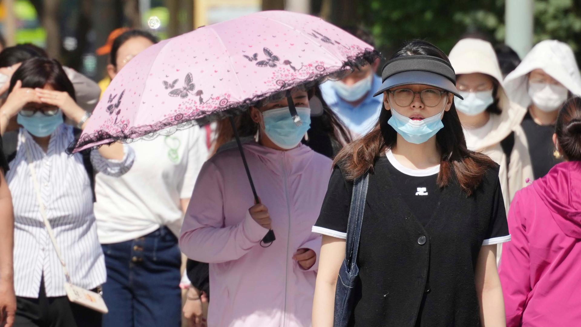 Menschen in Peking tragen eine medizinische Maske.