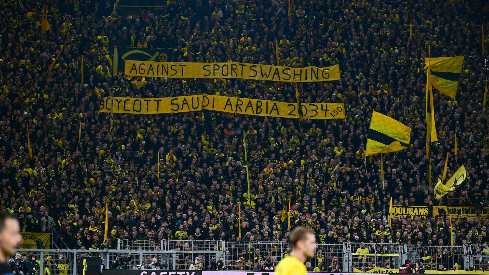 Bei einem Fußballspiel halten Fans ein Banner mit der Aufschrift "Against Sportswashing - Boycott Saudi Arabia 2034" in die Höhe.