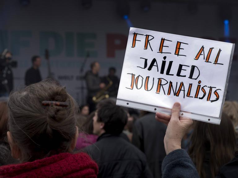 Eine Demonstrantin hält ein Schild mit der Aufschrift "Free all jailed Journalists".