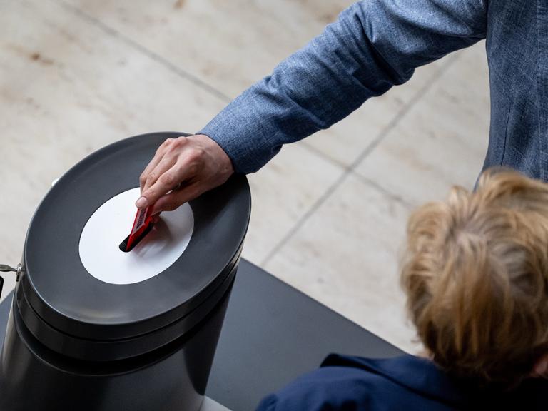 Die Hand eines Abgeordneter gibt während der Sitzung des Bundestag seine Stimmkarte ab