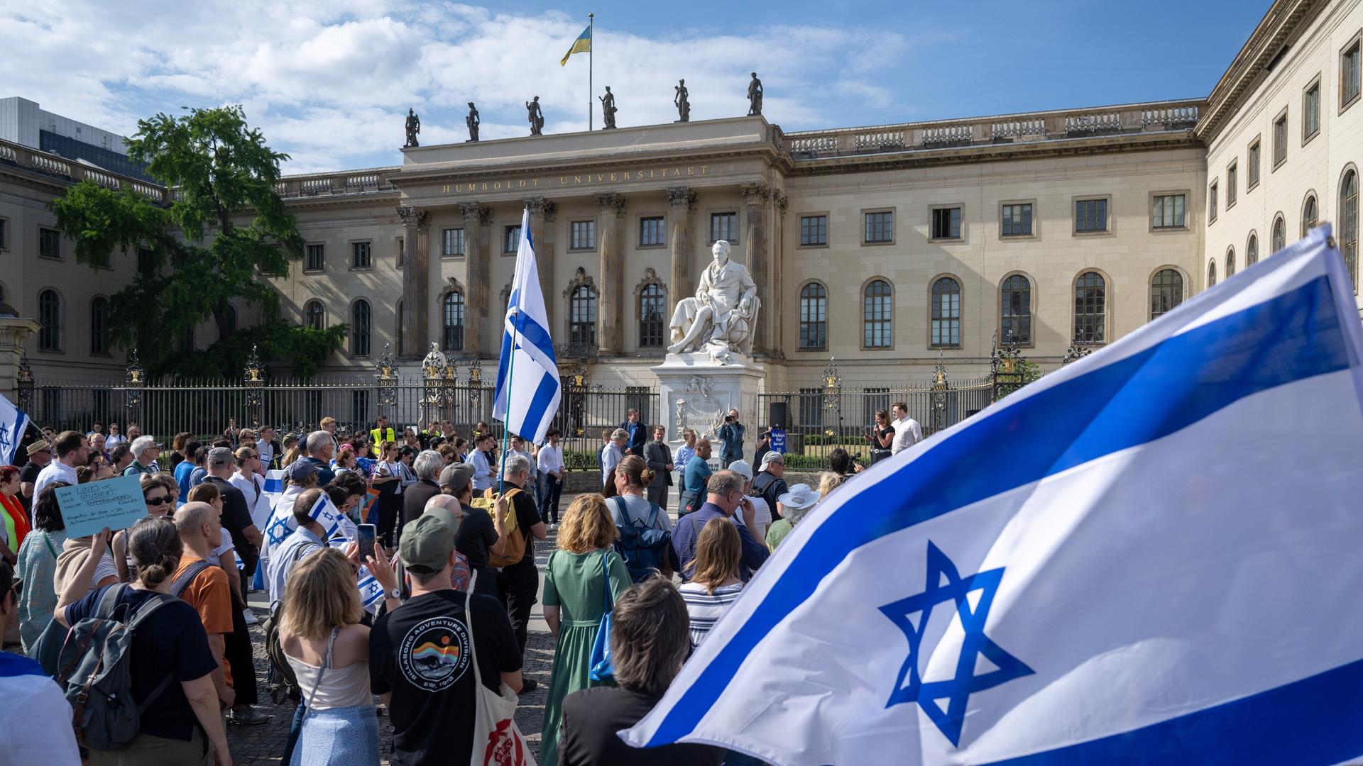 Teilnehmer stehen mit israelischen Fahnen bei einer Kundgebung vor der Humboldt-Universität in Berlin.