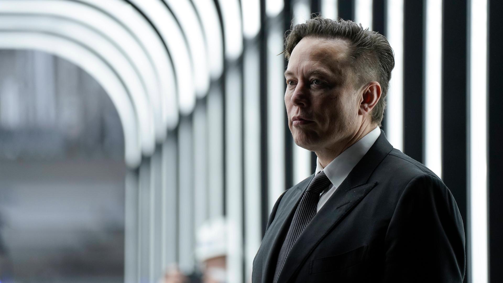 Elon Musk steht in einem Durchgang der Fabrik Tesla