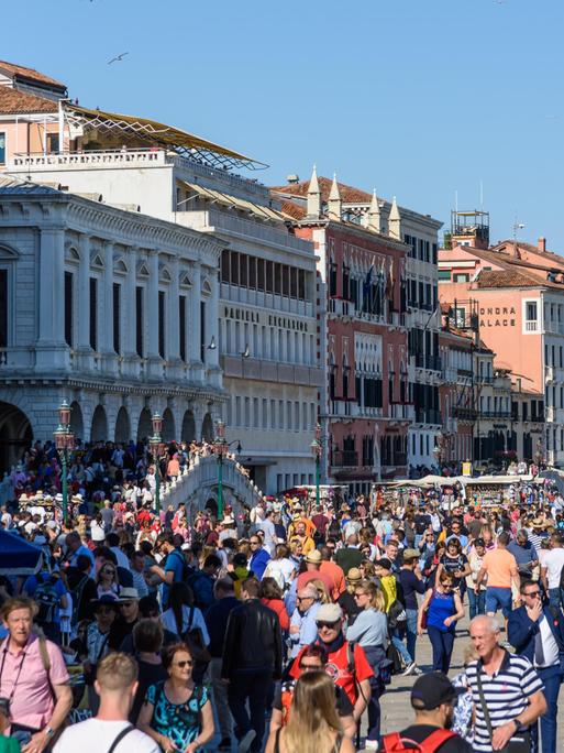 Sehr viele Menschen sind bei Sonnenschein auf einem Platz in Venedig zu sehen.