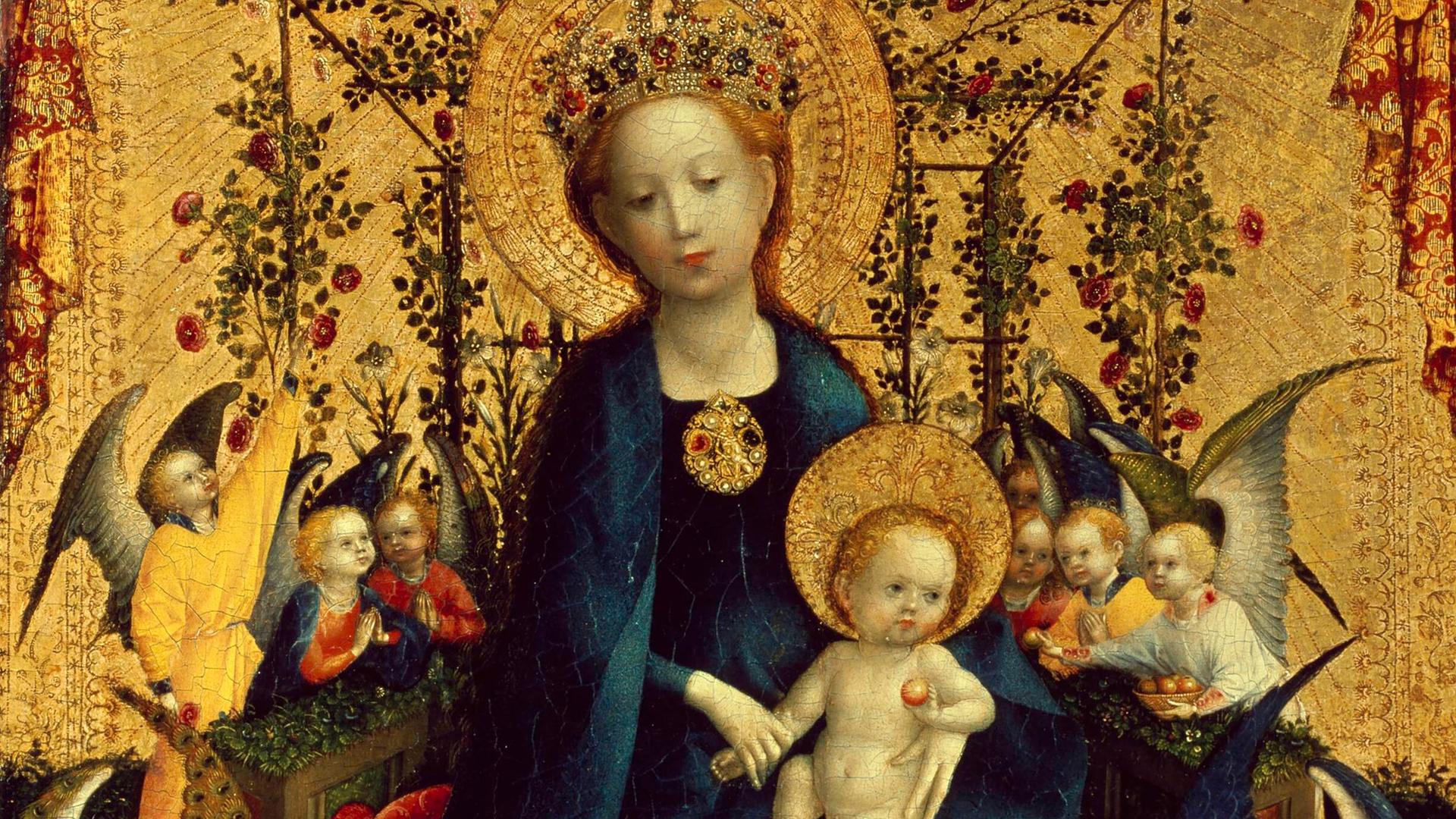 Das Bild "Muttergottes in der Rosenlaube" von Stephan Lochner zeigt ein Ölgemälde von Maria mit Jesus auf dem Schoß. Sie trägt ein blaues Gewand, Jesus ist nackt.