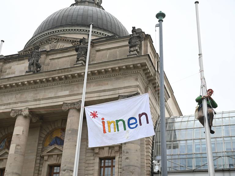 Schülerinnen und Schüler haben eine Flagge mit der Aufschrift "innen" in Regenbogenfarben an der Münchner Staatskanzlei angebracht. 3. April 2024