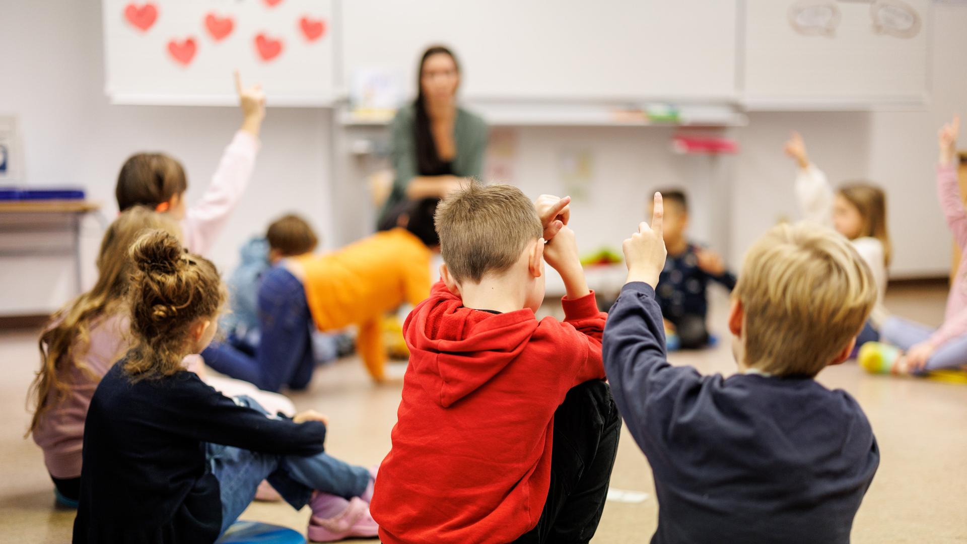 Schüler einer zweiten Klasse einer Grundschule im Stadtteil Neuperlach in München (Bayern) sitzen während des Unterrichts in einem Kreis auf dem Boden des Klassenzimmers zusammen und melden sich. Die Schule nimmt am Startchancen-Programm teil.