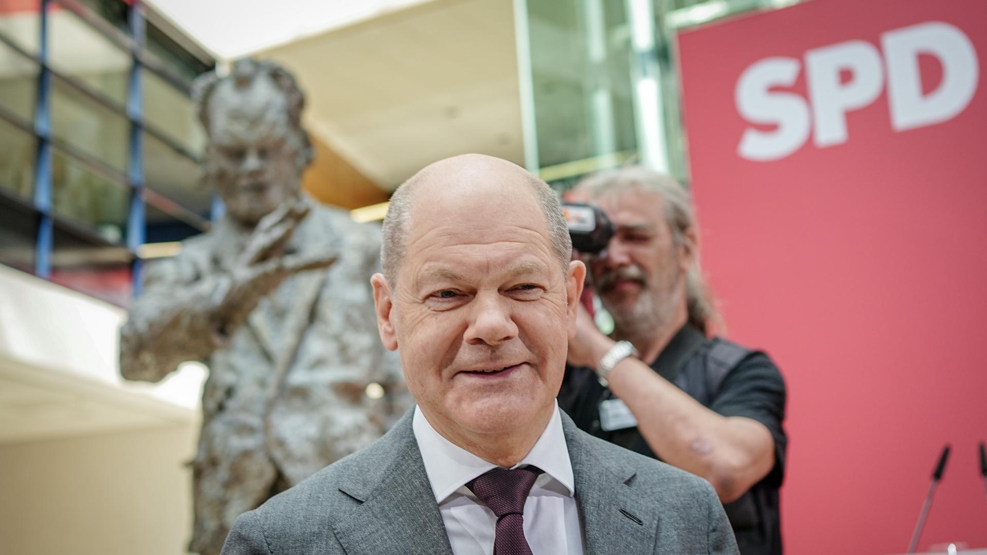 Bundeskanzler Olaf Scholz (SPD) nimmt an der Feier der SPD für ihr 160-jähriges Bestehen teil. Im Hintergrund  eine Büste von Willy Brand und der Schriftzug "SPD".