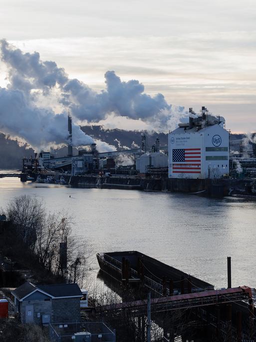 Die Kokerei Clairton von U. S. Steel liegt am Monongahela River in Clairton. Rauch steigt aus den Schornsteinen, an der Fassade des Gebäudes ist eine haushohe US-Flagge zu sehen.