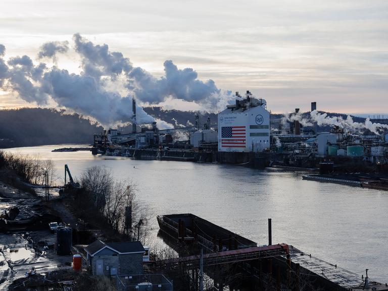 Die Kokerei Clairton von U. S. Steel liegt am Monongahela River in Clairton. Rauch steigt aus den Schornsteinen, an der Fassade des Gebäudes ist eine haushohe US-Flagge zu sehen.
