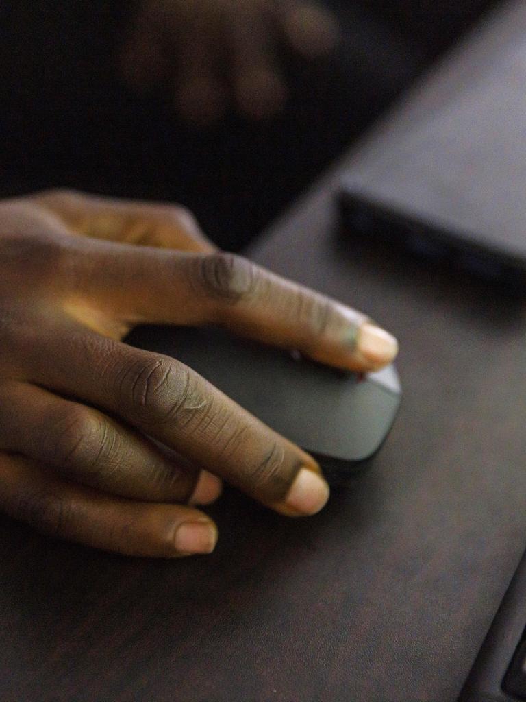 Rechte Hand an einer Computermaus vor einer Computertastatur