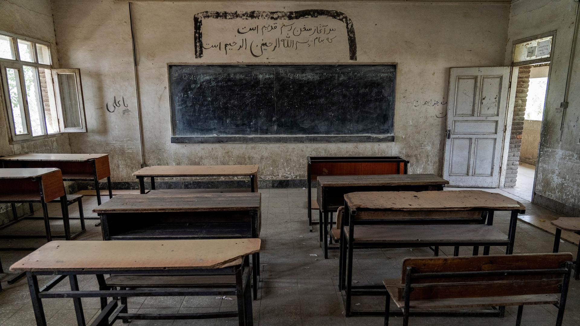 Ein leeres Klassenzimmer mit Blick auf eine Tafel an der Wand und Holztischen und Sitzen in einer Mädchenschule, die von den Taliban geschlossen wurde.