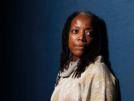 Schriftstellerin Tsitsi Dangarembga blickt vor dunkelblauem Hintergrund nachdenklich in die Kamera.