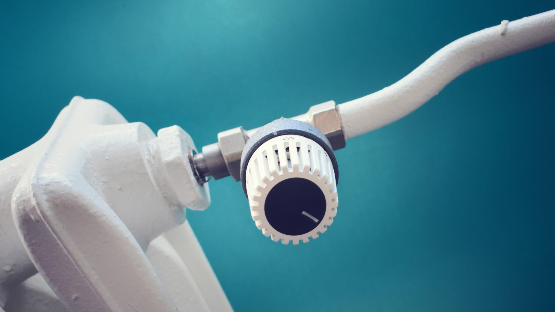 Eine weiße Heizung vor einer grün-blauen Wand. Eine weiße Heizung vor einer grün-blauen Wand.