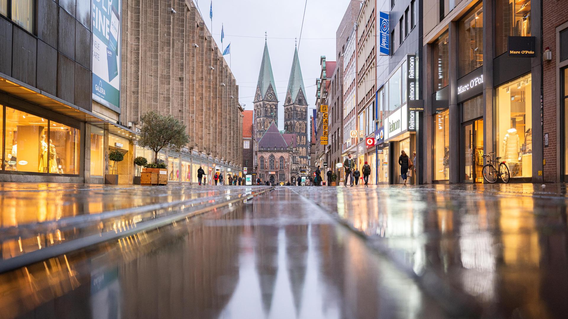 Blick in die Bremer Fußgängerzone mit nassem Pflaster. Im Hintergrund der St. Petri Dom.