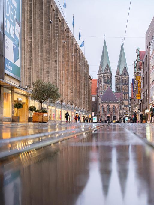 Blick in die Bremer Fußgängerzone mit nassem Pflaster. Im Hintergrund der St. Petri Dom.