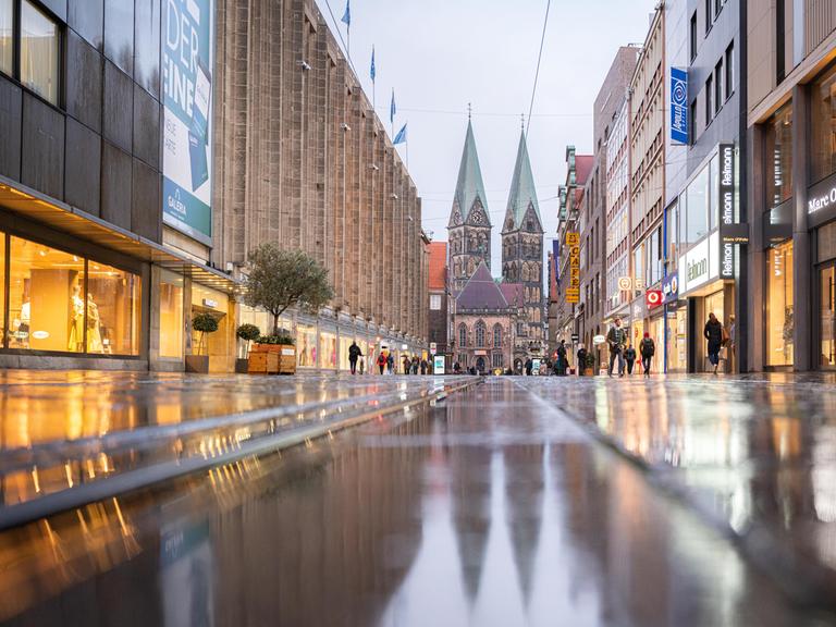 Blick in die Bremer Fußgängerzone mit nassem Pflaster. Im Hintergrund der St. Petri Dom.