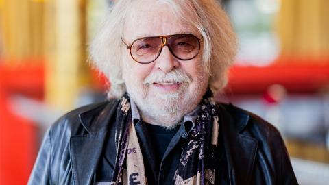 Zirkusdirektor Bernhard Paul mit weißem Schnurrbart und getönter Brille. Er trägt eine schwarze Lederjacke und zeigt ein freundliches Lächeln.