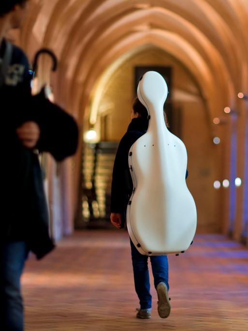 Eine Studentin der Hochschule für Musik und Theater in Rostock (Mecklenburg-Vorpommern) trägt ihr Cello durch einen Kreuzgang des Katharinenstifts.