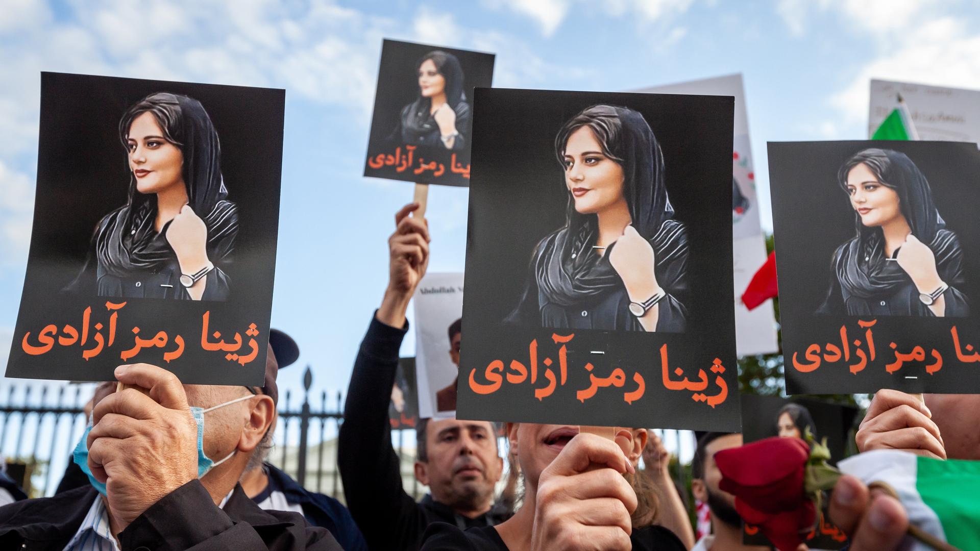 Demonstranten halten Schilder mit dem Bild von Mahsa Amini in die Höhe