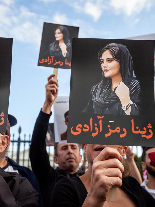 Demonstranten halten Schilder mit dem Bild von Mahsa Amini in die Höhe