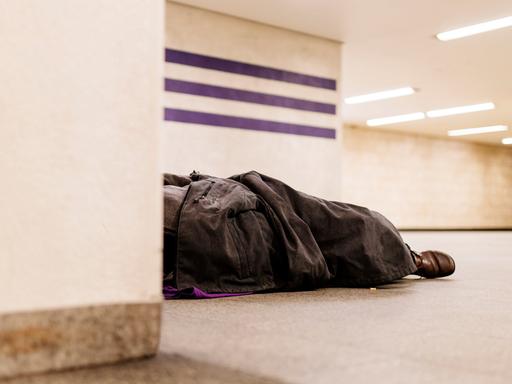 Ein Obdachloser schläft improvisiert unter einer Decke in einer U-Bahn-Haltestelle. Köln, 04.12.2019
