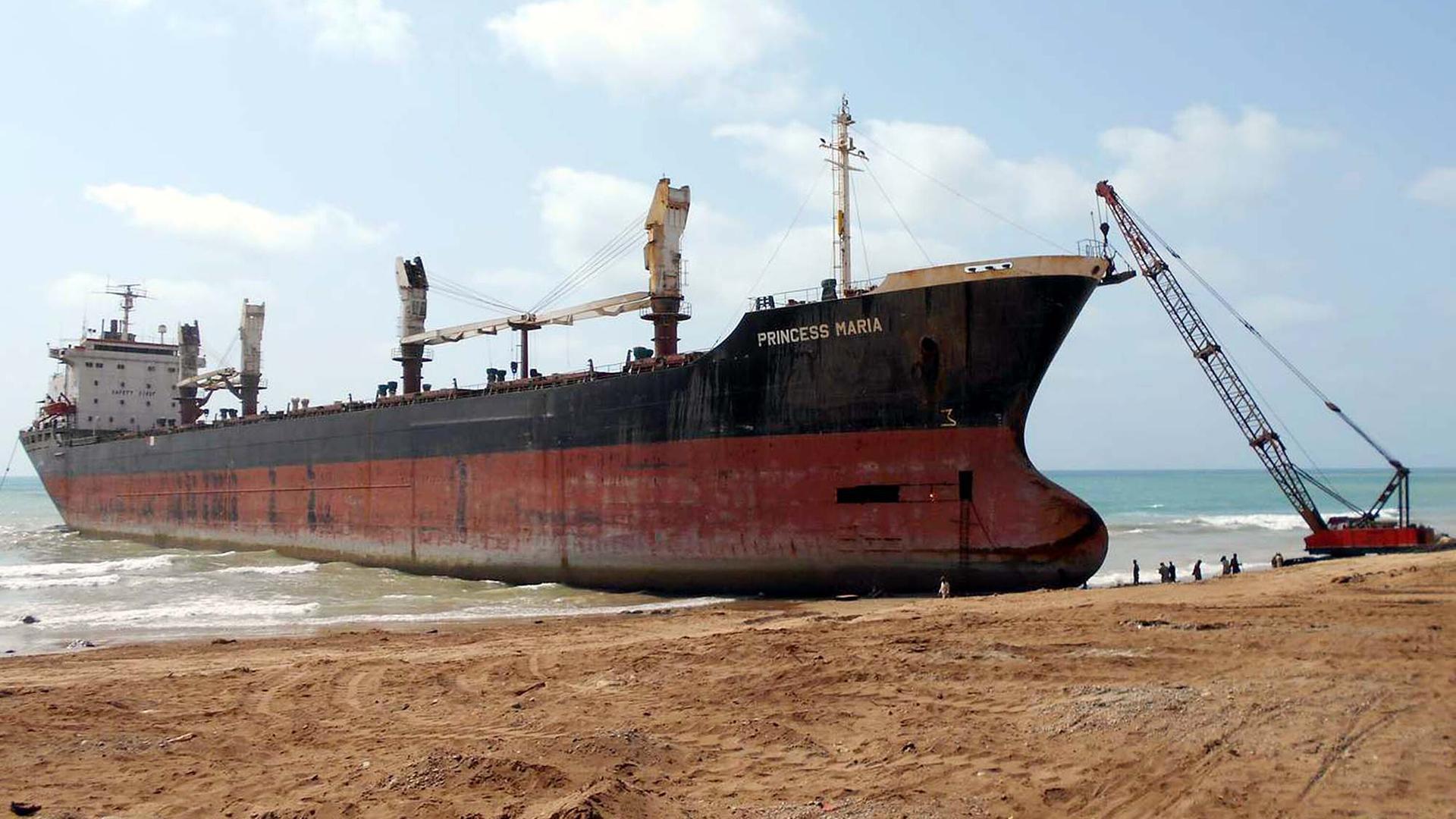 Das Schiff liegt am Strand. Daneben ein Kran und Arbeiter. Das Schiff liegt am Strand. Daneben ein Kran und Arbeiter.