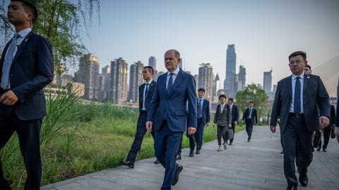 Bundeskanzler Olaf Scholz (SPD) geht in Shanghai eine Straße entlang. Neben und hinter ihm laufen mehrere Personen.