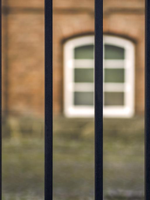 Blick durch ein Gitter auf einen Gefängnishof.