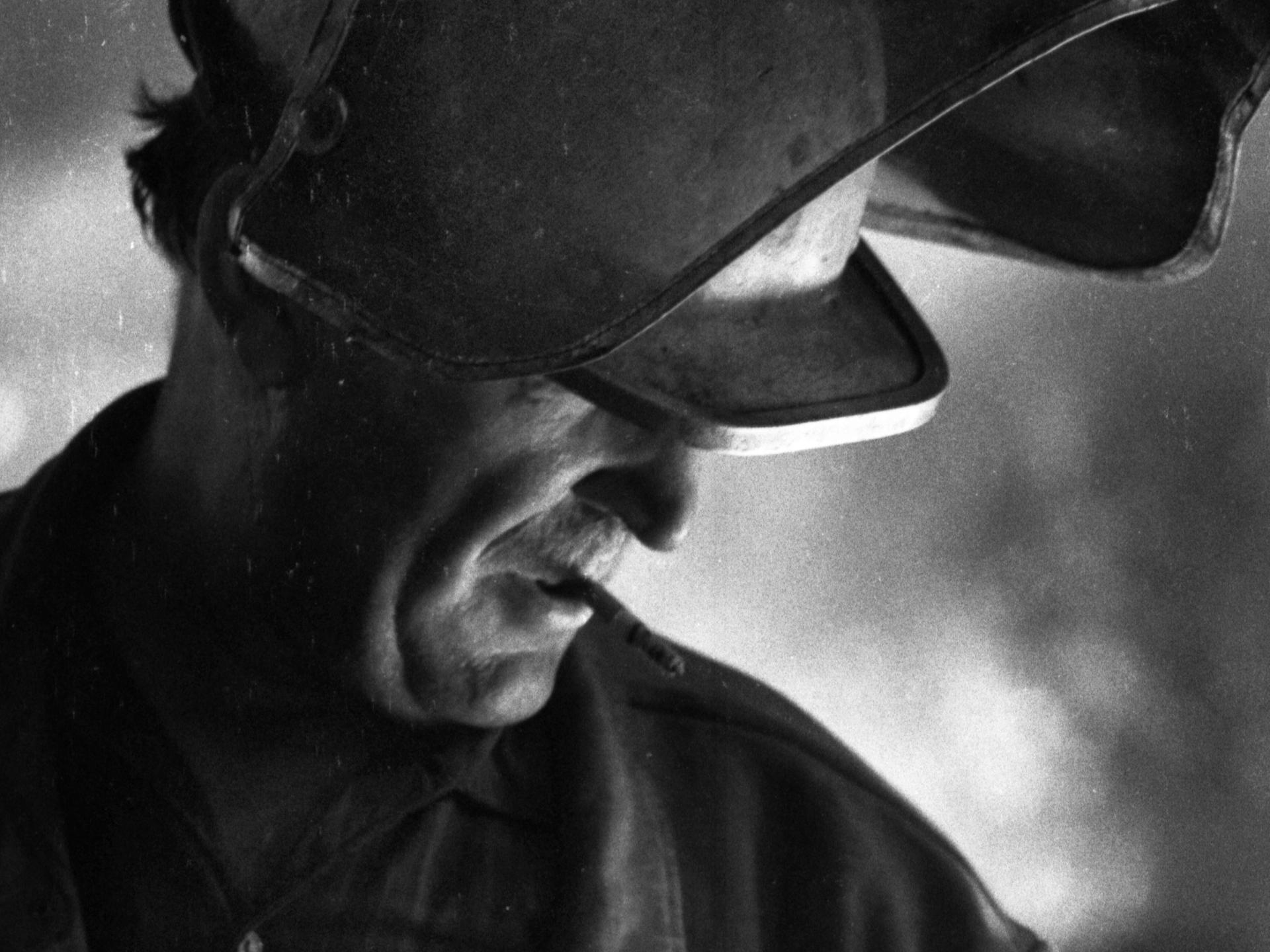 Historisches Schwarzweißfoto eines Zigarette rauchenden Arbeiters in Schutzkleidung am Hochofen. 1970 